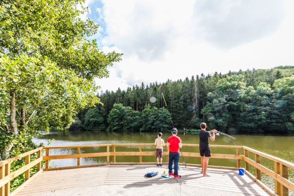Trois enfants sur un ponton pêchent dans une rivière